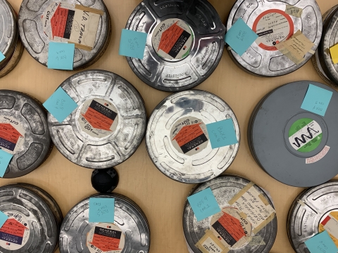 Film reels are laid out on a table and organized by title.